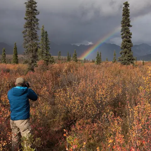 man photographing rainbow in alaska