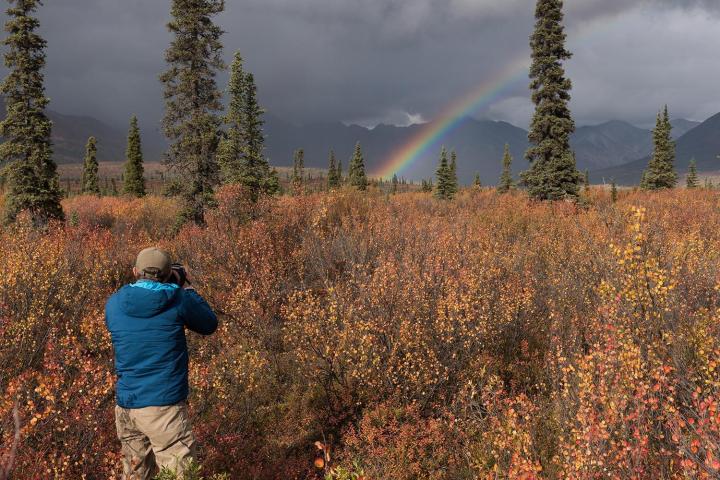 man photographing rainbow in alaska