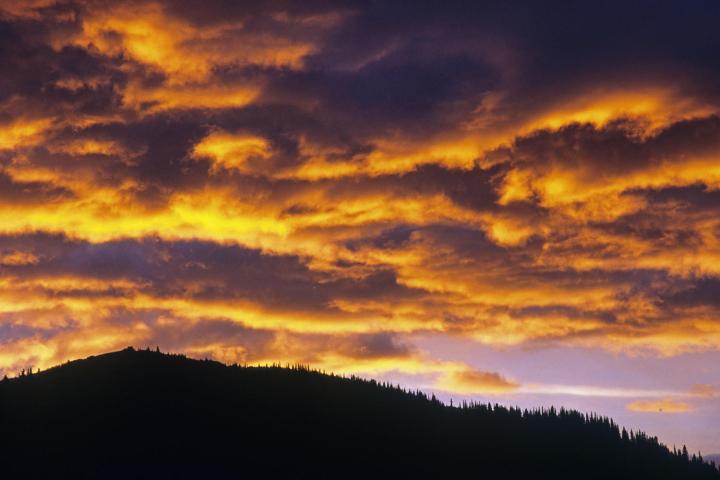 Orange clouds over a silouhette of a hill